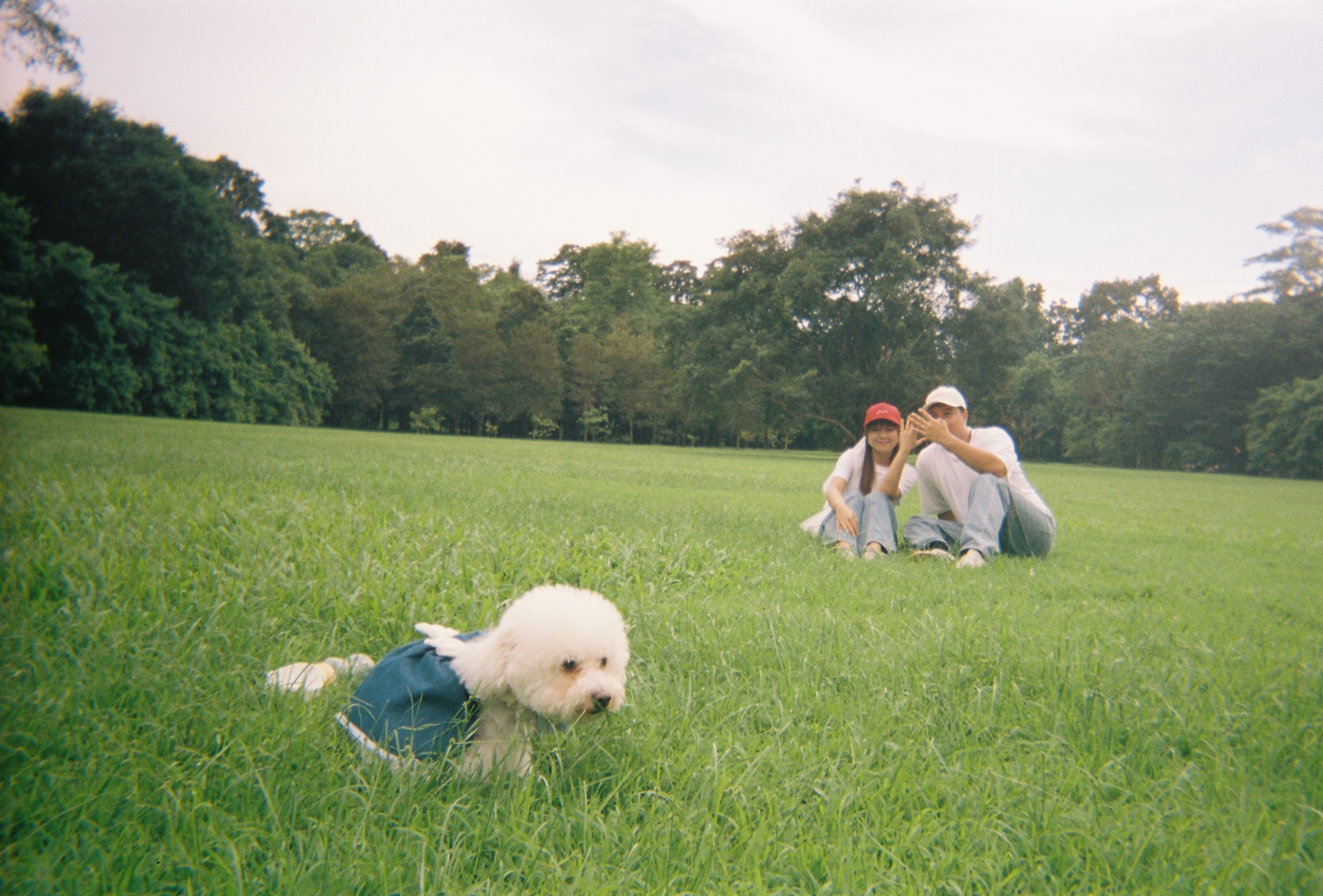 น้องหมาอยู่ด้านหน้า ขณะที่ 'Kham-pom และ Puen นั่งอยู่ด้วยกันกลางสนามหญ้า